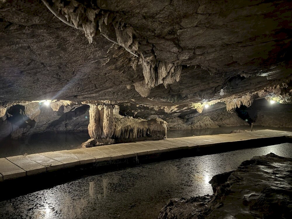 An underground stream flows gently through the cave, creating a cool and peaceful atmosphere
